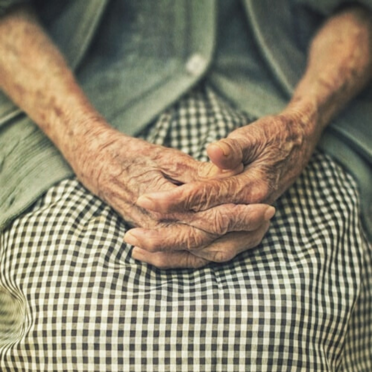 Elderly ladies hands crossed on top of her lap